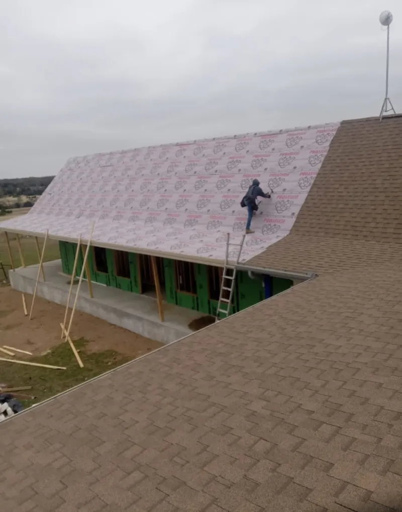 Worker preparing underlayment for a metal roof installation in Naugatuck